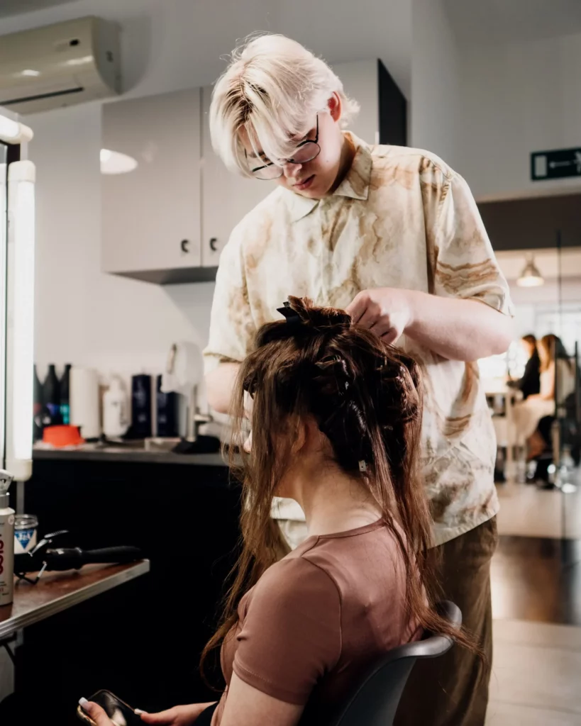 Fryzjer uczący się technik upinania włosów na kursie fryzjerskim dla początkujących