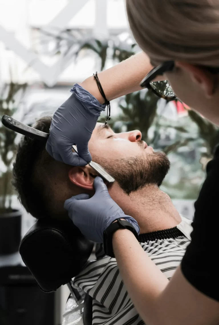 Trymowanie brody na kursie barberskim z wykorzystaniem techniki brzytwy przy konturze.
