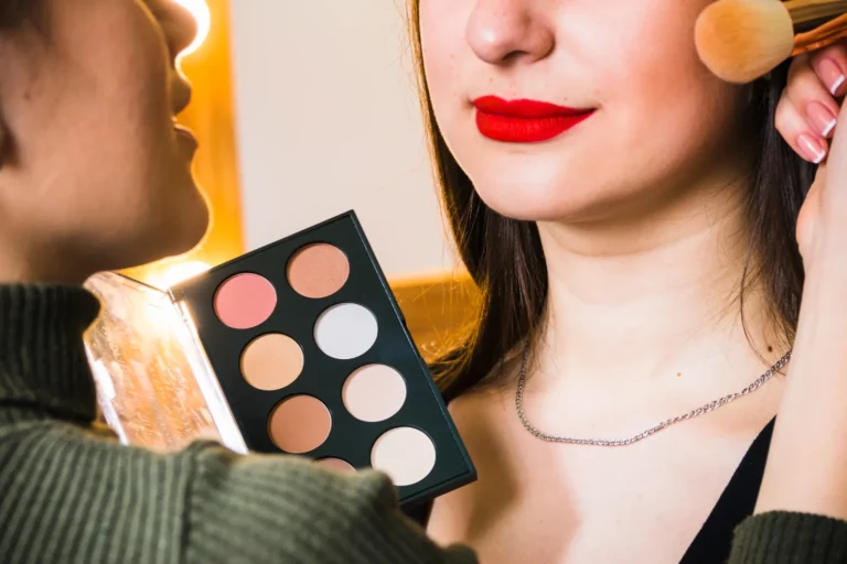 Uczestniczka kurs makijażu Warszawa uczy się konturowania policzków i nakładania różu pod okiem instruktorki.