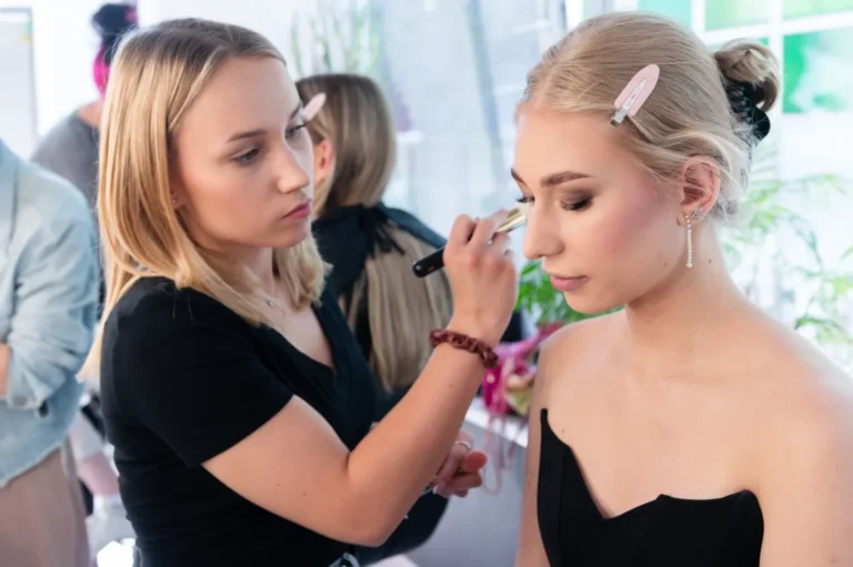 Wizażystka pracuje pędzlem na powiece modelki na zajęciach w szkoła wizażu Warszawa.