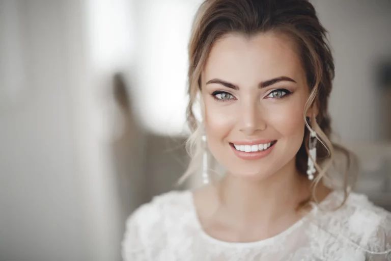 Kobieta w jasnej sukni ślubnej z delikatnym makijażem twarzy i podkreślonymi oczami, co odnosi się do tego, jak samemu zrobić makijaż ślubny.