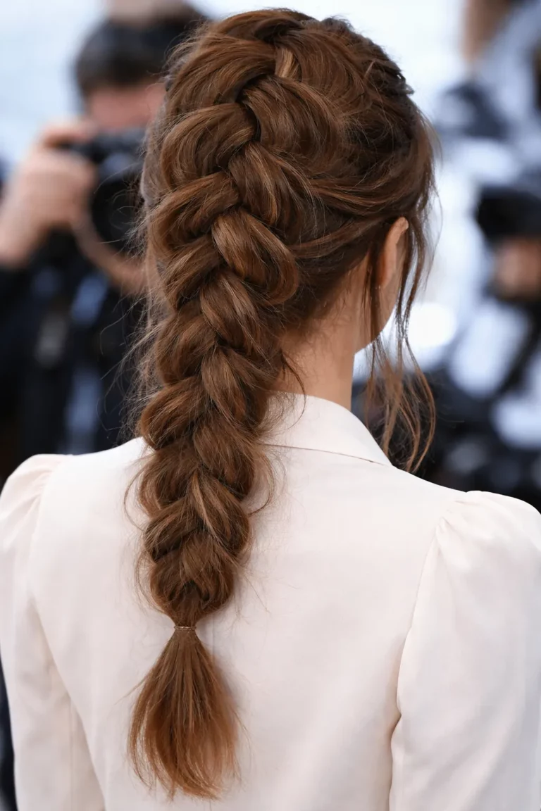 Tył głowy osoby na kursie fryzjerskim Warszawa z brązowymi włosami zaplecionymi w warkocz dobierany.